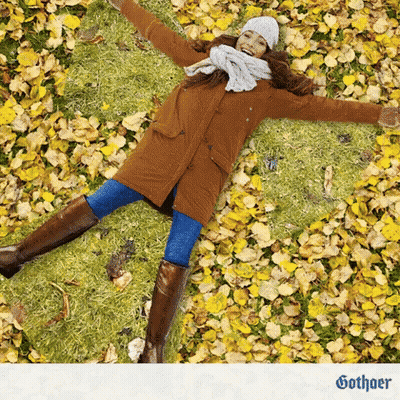 Woman In Brown Coat Laying On Yellow Leaves GIF