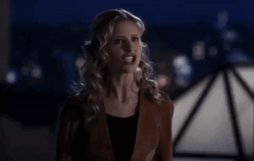 Woman In Brown Jacket In Front Of Dark Background GIF