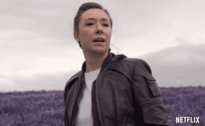 Woman In Brown Leather Jacket Running Through Purple Flowers GIF