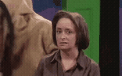 Woman In Brown Shirt In Front Of Green Door GIF