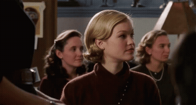 Woman In Brown Sweater Standing In Line With Others GIF