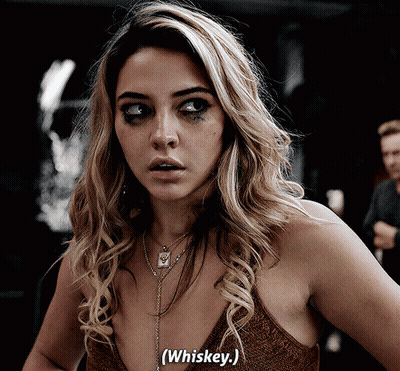Woman In Brown Top Saying Whiskey In Dark Room GIF