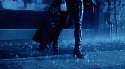 Woman In Cape And Boots Walking Through Rain GIF