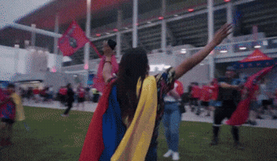 Woman In Cape Holding Flag In Crowd GIF