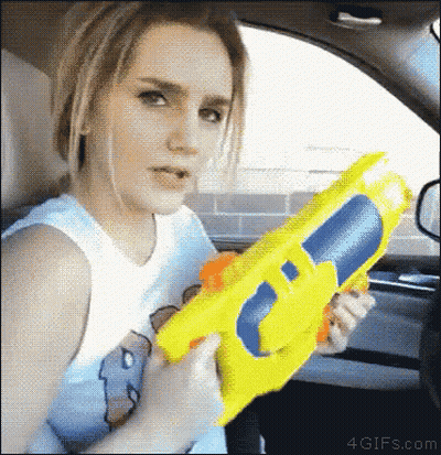 Woman In Car Holding Yellow Water Gun GIF