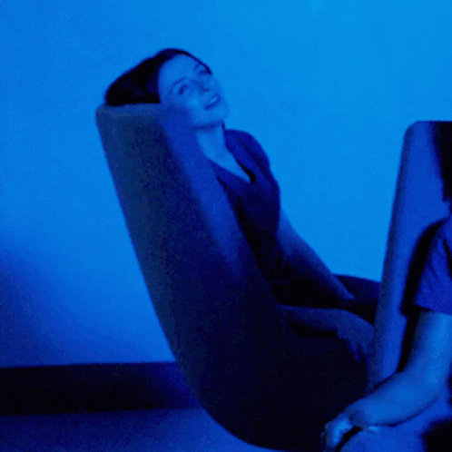 Woman In Chair With Blue Light In Dark Room GIF