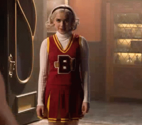 Woman In Cheerleader Costume Standing In Front Of Door GIF