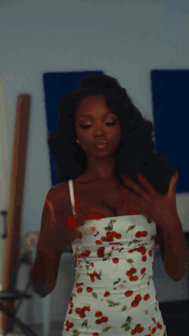 Woman In Cherry Print Dress In Front Of Blue Wall GIF