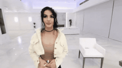 Woman In Choker And White Jacket Standing In Living Room GIF