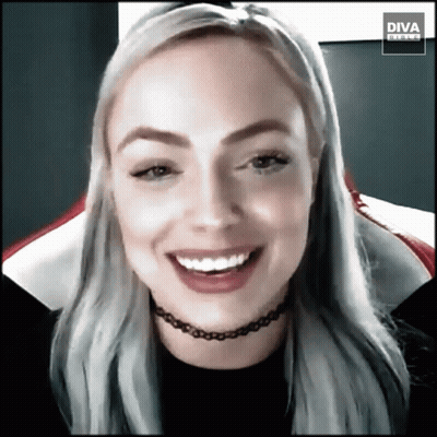 Woman In Choker Smiling In Front Of Diva Banner GIF
