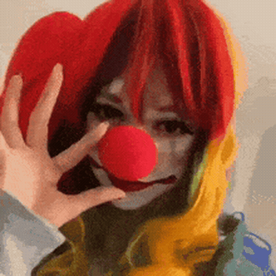 Woman In Clown Costume Holding Red Nose GIF