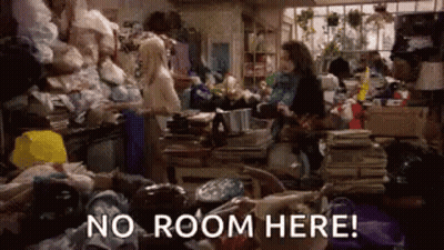 Woman In Cluttered Room With No Room Here Sign GIF