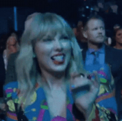 Woman In Colorful Dress Sitting In Crowd GIF
