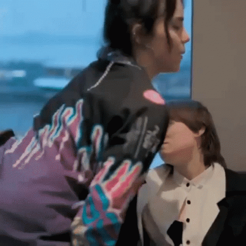 Woman In Colorful Jacket Kissing Man In Suit GIF