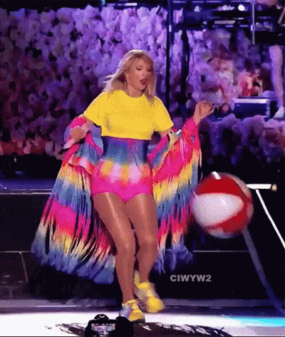 Woman In Colorful Outfit Holding Beach Ball On Stage GIF