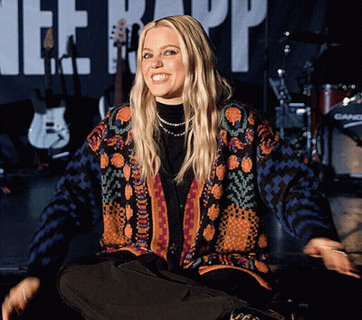 Woman In Colorful Sweater Sits In Front Of Therapy Banner GIF