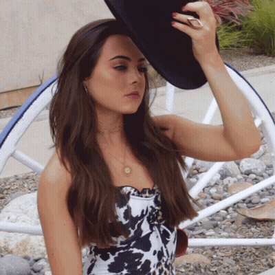 Woman In Cow Print Top Adjusting Black Hat GIF