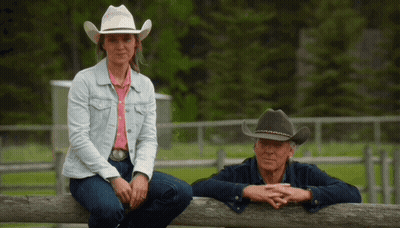 Woman In Cowboy Hat Next To Man Leaning On Wooden Fence GIF