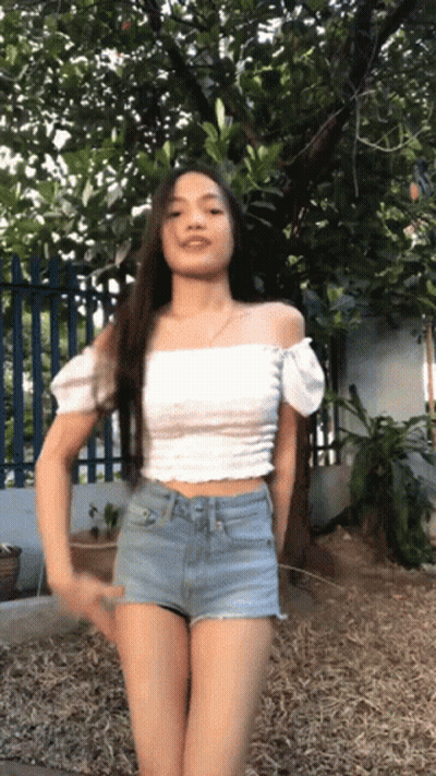 Woman In Crop Top And Shorts Arms Outstretched On Beach GIF