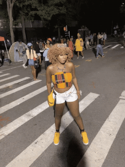 Woman In Crop Top And Shorts Crossing Street At Night GIF