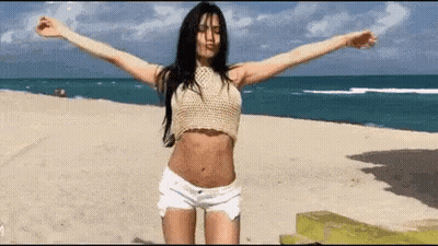 Woman In Crop Top And Shorts With Arms Outstretched On Beach GIF