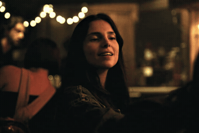 Woman In Denim Jacket Sitting In Dark Room GIF