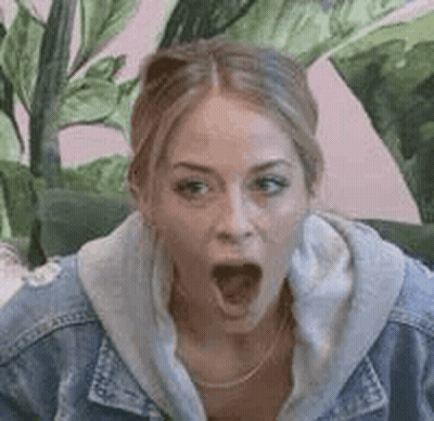 Woman In Denim Jacket Sitting On Couch With Mouth Open GIF