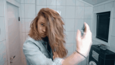 Woman In Denim Jacket Spraying Hair GIF
