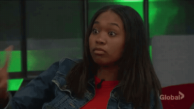 Woman In Denim Jacket Waving In Front Of Green Wall GIF