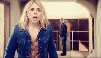 Woman In Denim Jacket With Man Behind Her In Hallway GIF