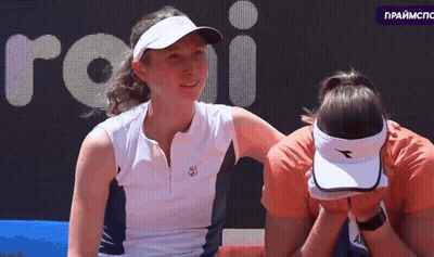 Woman In Diadora Hat Covering Face With Another Woman Looking On GIF