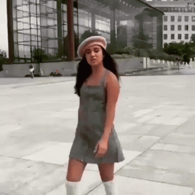 Woman in Dress and Beret Dancing on Sidewalk