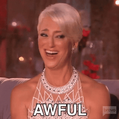 Woman In Dress And Necklace Smiling On Couch GIF