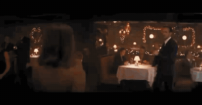 Woman In Dress Looking Over Shoulder In Restaurant GIF