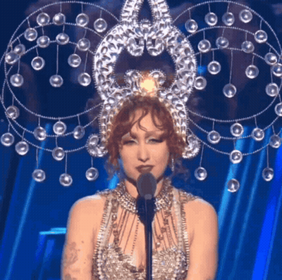 Woman In Elaborate Costume At Microphone GIF
