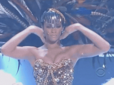 Woman In Feathered Headdress And Gold Top GIF