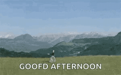 Woman In Field With Mountains Saying Goofd Afternoon GIF