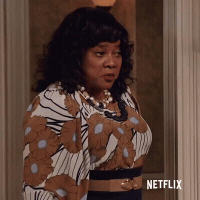 Woman In Floral Dress In Front Of Netflix Sign GIF