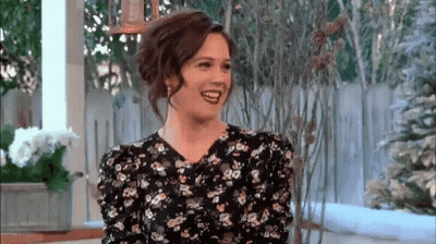 Woman In Floral Dress Smiling And Laughing On Porch GIF
