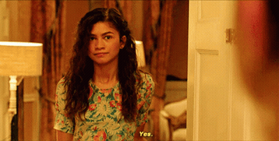 Woman In Floral Dress Standing In Front Of Door GIF
