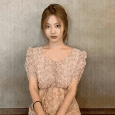 Woman In Floral Dress Standing In Front Of Wall GIF