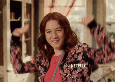 Woman In Floral Jacket Arms In Air GIF