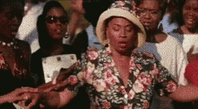 Woman In Floral Shirt And Hat Standing In Crowd GIF