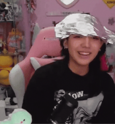 Woman In Foil Hat Smiling In Pink Chair GIF