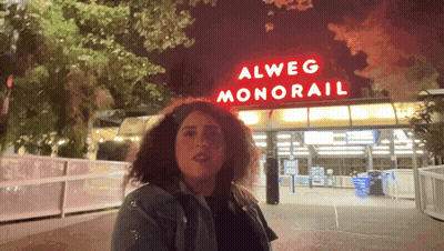 Woman In Front Of Alweg Monorail Sign GIF