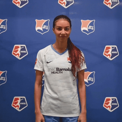 Woman In Front Of Blue Wall Saying NW Barnaba Health GIF