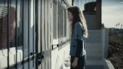 Woman In Front Of Building With Fence GIF