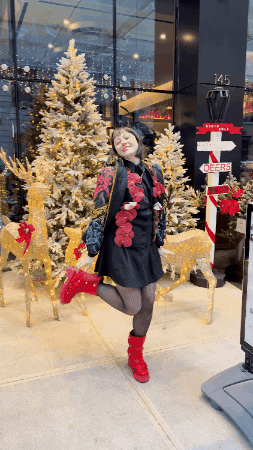 Woman In Front Of Christmas Tree With Sign Saying North Pole GIF