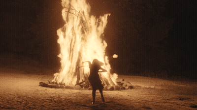 Woman In Front Of Large Burning Fire GIF