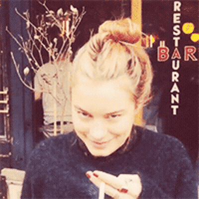 Woman In Front Of Restaurant Sign GIF